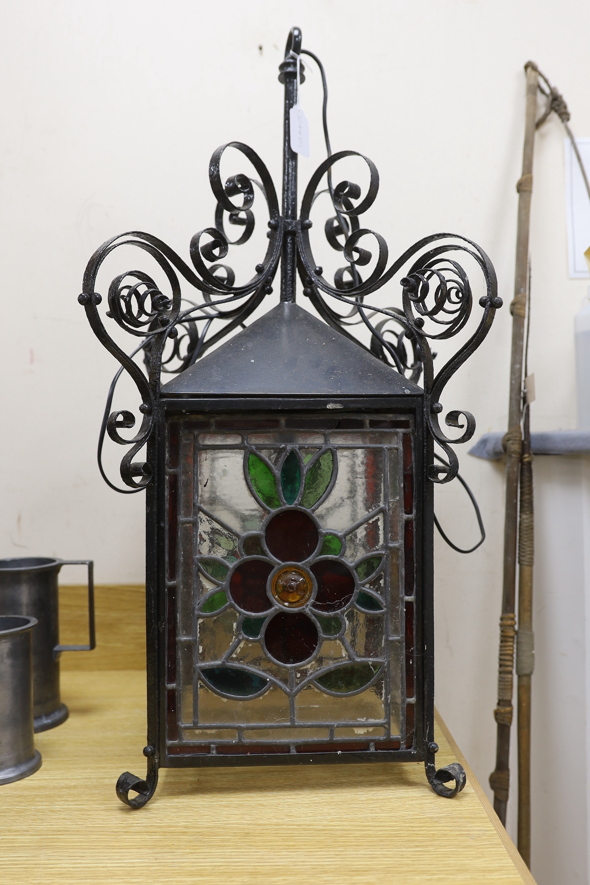 A late 19th/early 20th century Arts and Crafts style wrought iron and stained glass panelled hanging lantern, 80cms high